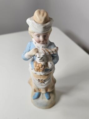 antique German bisque porcelain figurine of a Victorian girl holding a puppy.